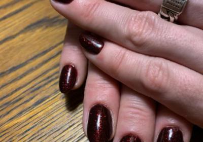 Hand met bordeaux kleur nagellak en glitters