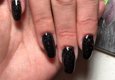 Hand met zwarte glitters nagellak